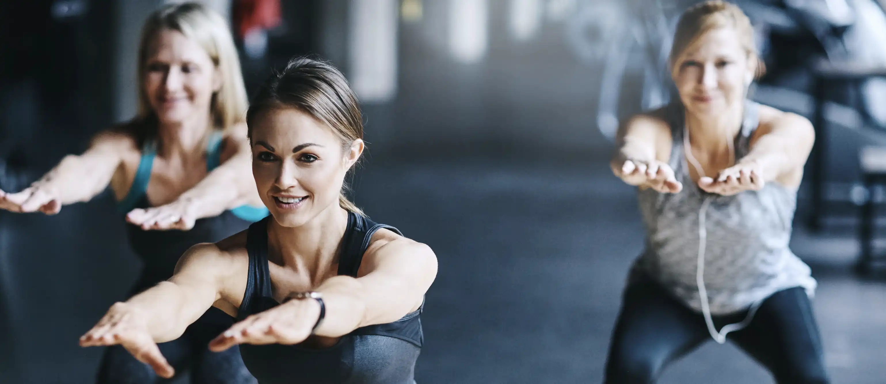 Drei Frauen, die Kniebeugen machen.
