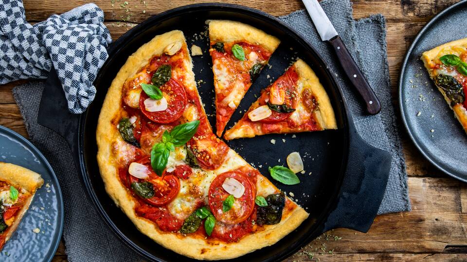 Der fluffige Teig macht diese American Pizza mit Mozzarella, Basilikum, Tomaten und Knoblauch doppelt lecker – zum reinbeißen!  