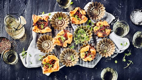 Garantiert der Hingucker auf jeder Party- Probieren Sie unser Rezept für Blätterteigtörtchen mit Tomaten und Zwiebeln in Muffinförmchen gebacken.
