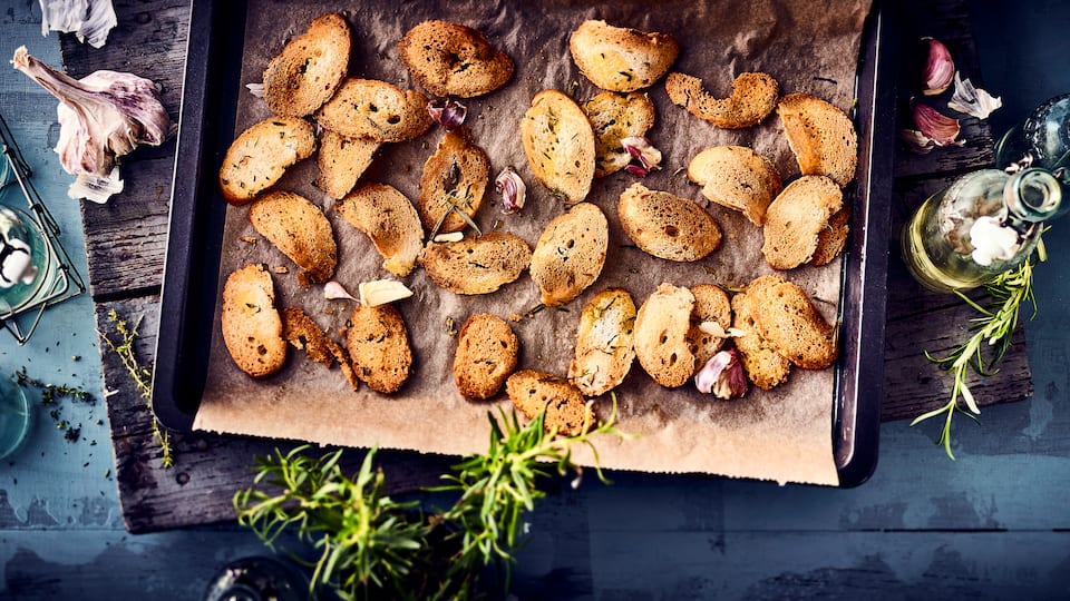 Ideal als kleiner Snack vor der Vorspeise oder als Chips-Ersatz zum Knabbern: Selbstgemachte Brotchips mit frischen Kräutern und Knoblauch. 