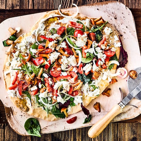 Frisch und lecker und mal was anderes: Probieren Sie unsere bunte Salatpizza mit Pflücksalat, Paprika, Pfifferlingen, Cocktailtomaten und Fetakäse – ein Genuss!
