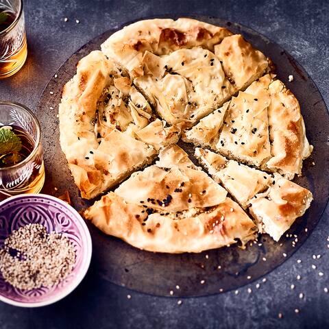 Blatt für Blatt wird der Yufka-Teig geschichtet, bepinselt und nach und nach mit Feta-Käse bestreut. So entsteht leckerer Burek mit Käse. 