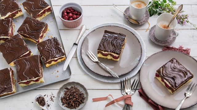 Typisches Wellenmuster auf der Schokolade, zweifarbiger Kuchenteig, fruchtige Kirschen und Buttercreme – das macht eine Donauwelle aus. Mit unserem Rezept gelingt Ihnen der Klassiker.