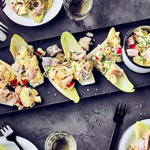 Kartoffelsalat mit Matjes, Gurke und Apfel, im Chicoreeblatt serviert.