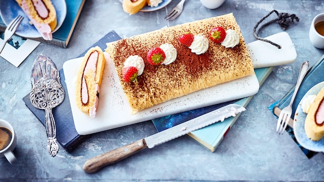 Probieren Sie unser Rezept für eine Erdbeer-Biskuitroulade gefüllt mit einer fruchtigen Quarkcreme mit Sahne und Nuss-Nougat einmal aus – sommerlich frisch!