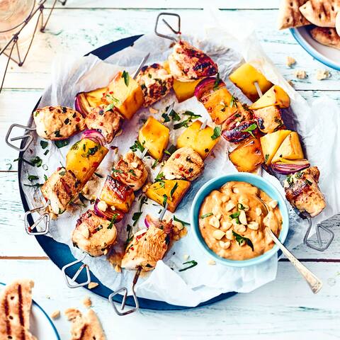 Die zarten Hähnchenspieße mit Erdnusssauce können Sie sowohl auf dem Grill als auch in der Pfanne zubereiten. Probieren Sie jetzt das originelle Rezept mit gegrillter Mango aus!