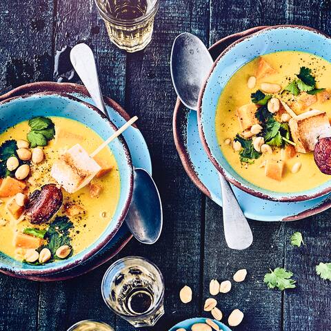 Ein wahres Geschmackserlebnis: Würzige vegane Erdnusssuppe mit viel frischem Gemüse und dazu leckeren Tofu-Spießen und frischer Koriander!