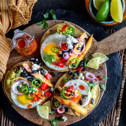 Toast zum Frühstück kennen wir alle, aber probieren Sie doch einmal diese selbstgemachten spanischen Frühstücks-Tostadas aus Maistacos mit Guacamole, Mais, Bohnen, Feta und Spiegelei.