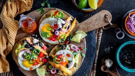 Toast zum Frühstück kennen wir alle, aber probieren Sie doch einmal diese selbstgemachten spanischen Frühstücks-Tostadas aus Maistacos mit Guacamole, Mais, Bohnen, Feta und Spiegelei.