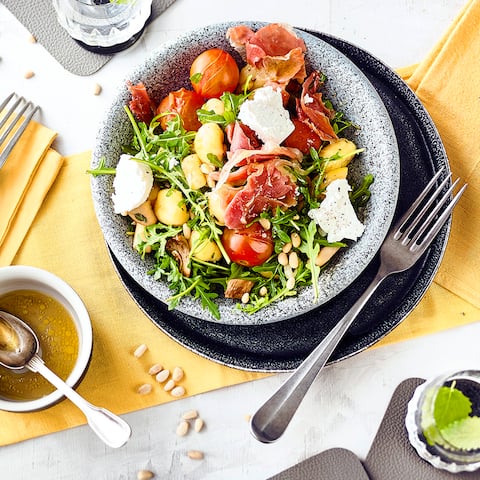 Ein Salat mit leckerem und sättigendem Inhalt: Unser Rezept für einen Gnocchi-Salat mit frischen Gnocchi, Kräuterseitlingen, Serrano-Schinken, Rucola und Ziegenkäse. Dazu passt eine Honig-Vinaigrette.