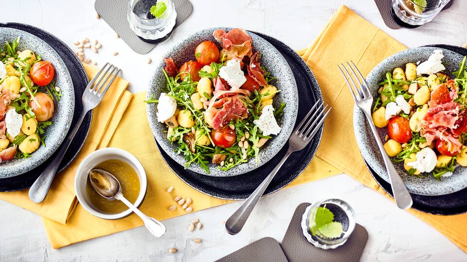 Ein Salat mit leckerem und sättigendem Inhalt: Unser Rezept für einen Gnocchi-Salat mit frischen Gnocchi, Kräuterseitlingen, Serrano-Schinken, Rucola und Ziegenkäse. Dazu passt eine Honig-Vinaigrette.