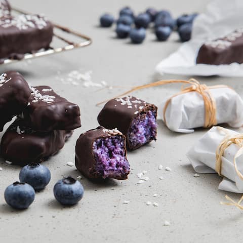 Blaubeeren geben unserem gesunden Kokos-Riegel das fruchtige Etwas, Mandeln, Kokosflocken und Agavendicksaft sorgen für eine süße Füllung.