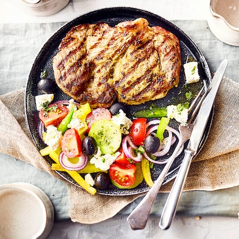 Perfekt für den Grill: Mit unserem Rezept zaubern Sie ein saftiges Nackensteak mit mediterranem Bauernsalat und Fladenbrot auf die Teller Ihrer Gäste.
