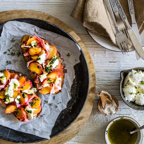 Fruchtige Crostini mit Plattpfirsichen und Büffelmozzarella: Eine sommerliche Vorspeise für laue Grillabende. 