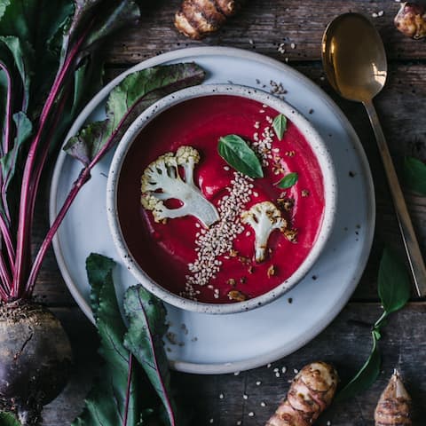 Rote-Bete-Topinambur-Suppe mit Kokosmilch, gerösteten Blumenkohlscheiben und Topinambur-Chips. 