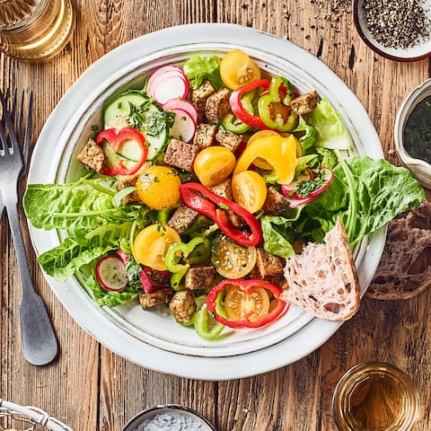 Knackig frische Salatherzen mit Mini-Paprika, Kirschtomaten, Salatgurke, Radieschen und Rucola, als Topping gebratener Kräuter-Tofu. 