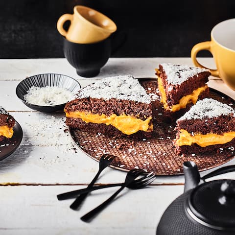 Cremiges Kürbispürree zwischen zwei schokoladigen Kuchenböden getoppt mit köstlichen Kokosraspeln - unser herbstlicher Kürbis-Schoko-Kuchen besticht mit jeder Menge Aromen. 