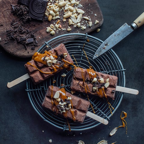 Ein Schokoladen-Eis-Traum erwartet Sie bei unserem Rezept für selbstgemachte Schokoladen-Eis-Pops mit Karamellsauce und gehackten Erdnüssen. 
