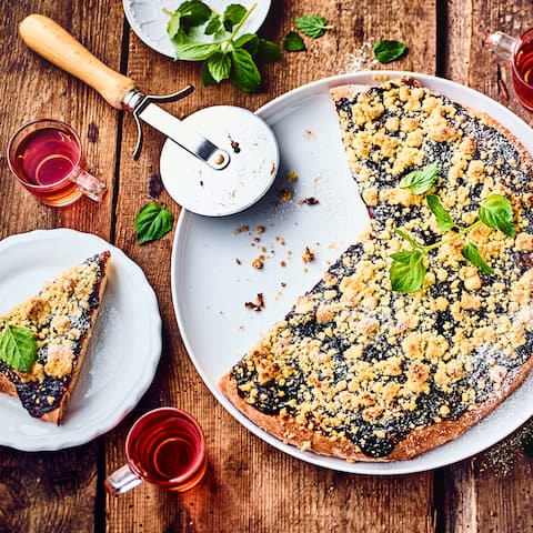 Unser Rezept für süße Pizza interpretiert den Klassiker der italienischen Küche auf unerwartete Weise und kombiniert ihn mit saftigen Pflaumen und zarten Streuseln.
