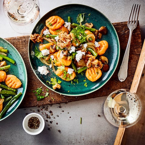 Italienischer Pasta-Klassiker mal anders! Unser Rezept für Süßkartoffel-Gnocchi besteht aus selbstgemachten Gnocchi und einer aromatischen Beilage mit Ziegenkäse, Walnüssen, Champignons und Bohnen. 