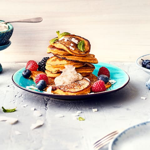 Pfannkuchen einmal anders: Probieren Sie unser Rezept für Süßkartoffel-Pancakes mit Dinkelmehl, frischen Beeren und Kokoschips aus – fruchtig und exotisch!