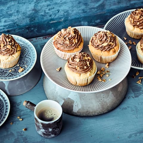 Kleine Küchlein mit Vanille-Soja-Joghurt und Walnüssen, mit einem Schokocreme-Frosting garniert.