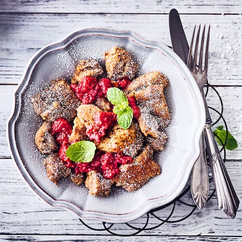 Köstlicher veganer Kaiserschmarrn mit Puderzucker und heißem selbstgemachtem Himbeerkompott ist nicht nur ein kleines Highlight des Tages.