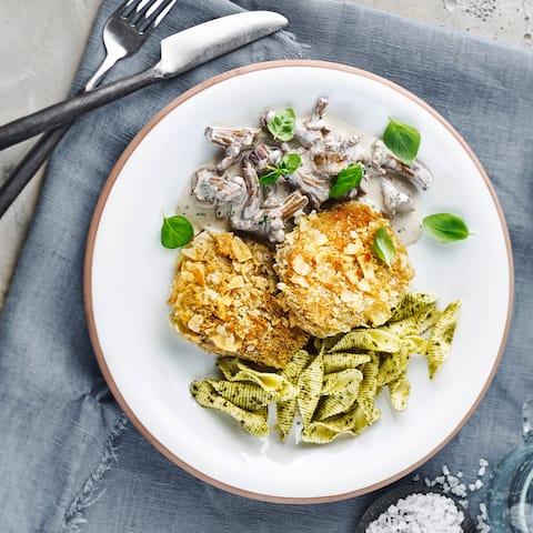 Ein echter Hingucker! Unser Rezept für Veganes Knusperschnitzel aus Seitan - kombiniert mit einer Pilzcreme aus Weißwein und Pesto-Pasta.