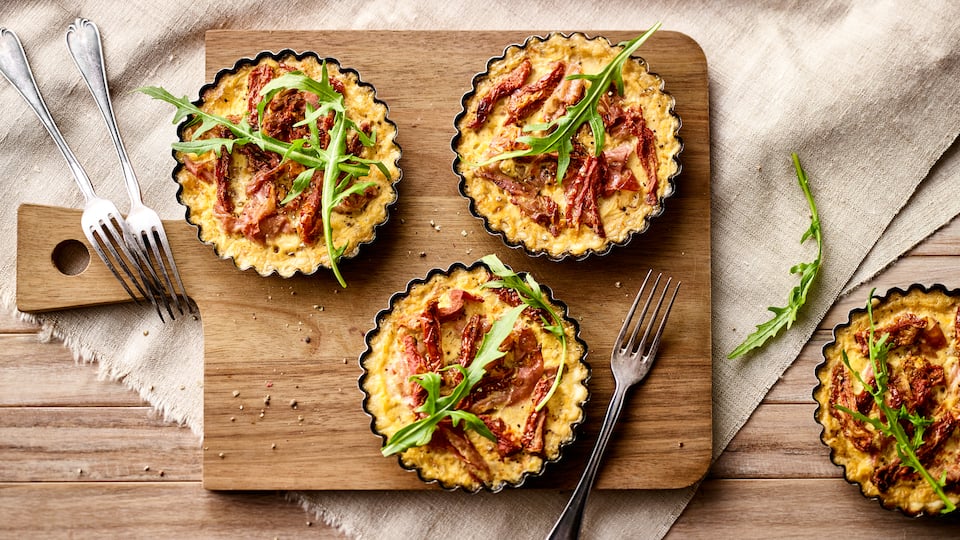 Unser Rezept für Mini-Quiche aus Mürbeteig gefüllt mit Parmaschinken, getrockneten Tomaten und Sahne eignet sich gut für jedes Buffet – gleich ausprobieren!