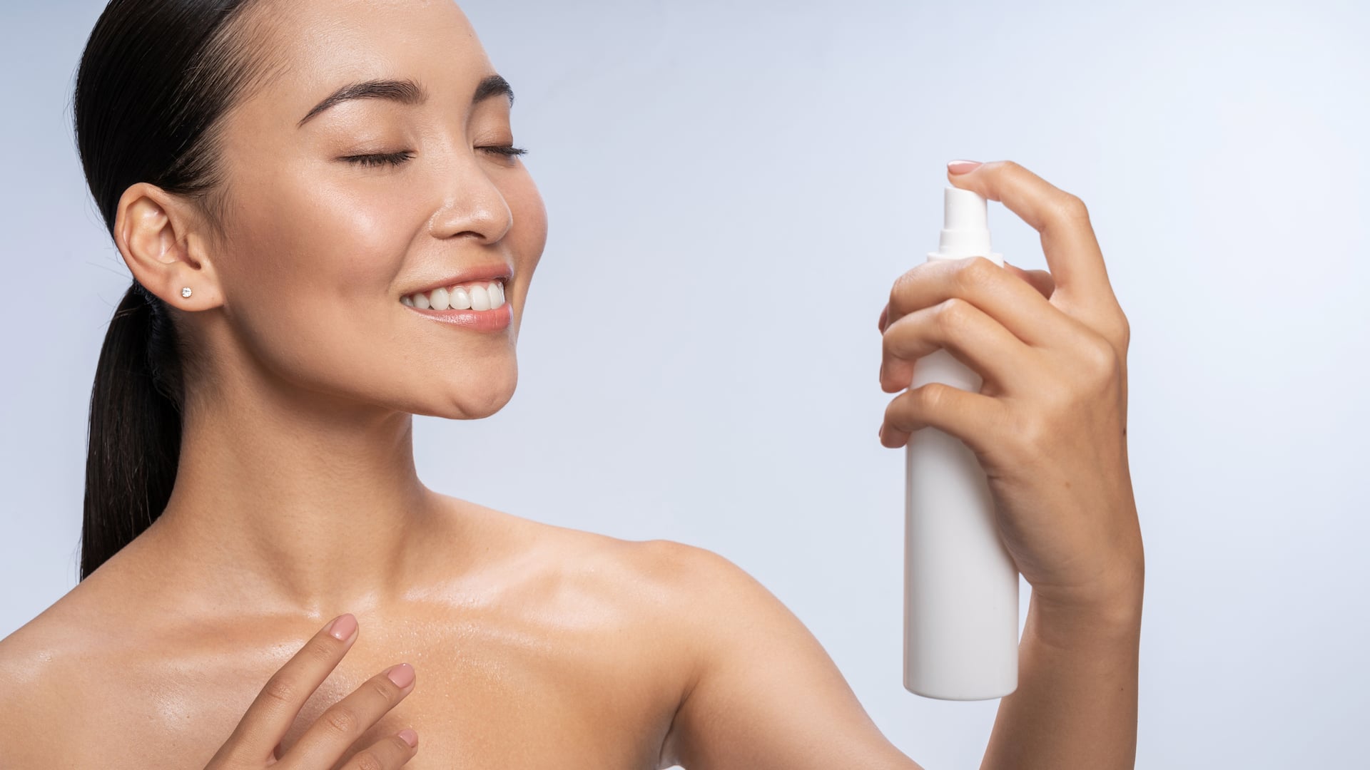 Frau sprüht Thermalwasser in ihr Gesicht.