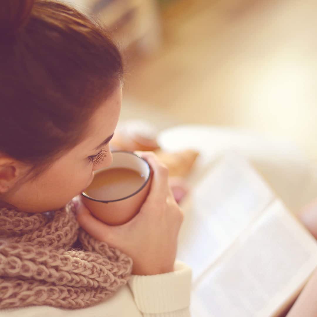 Frau trinkt Tee und ließt ein Buch