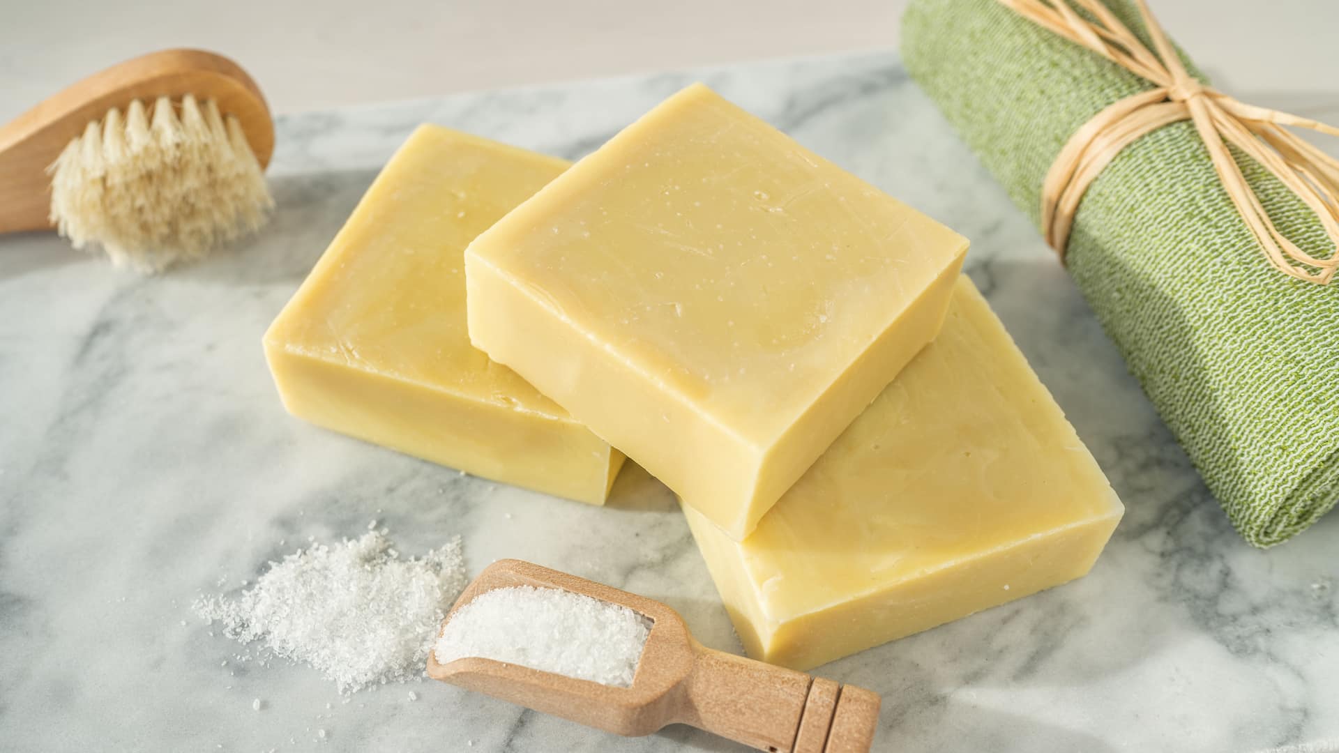 Drei Stücke Kernseife auf Mamoruntergrund neben Handtuch.