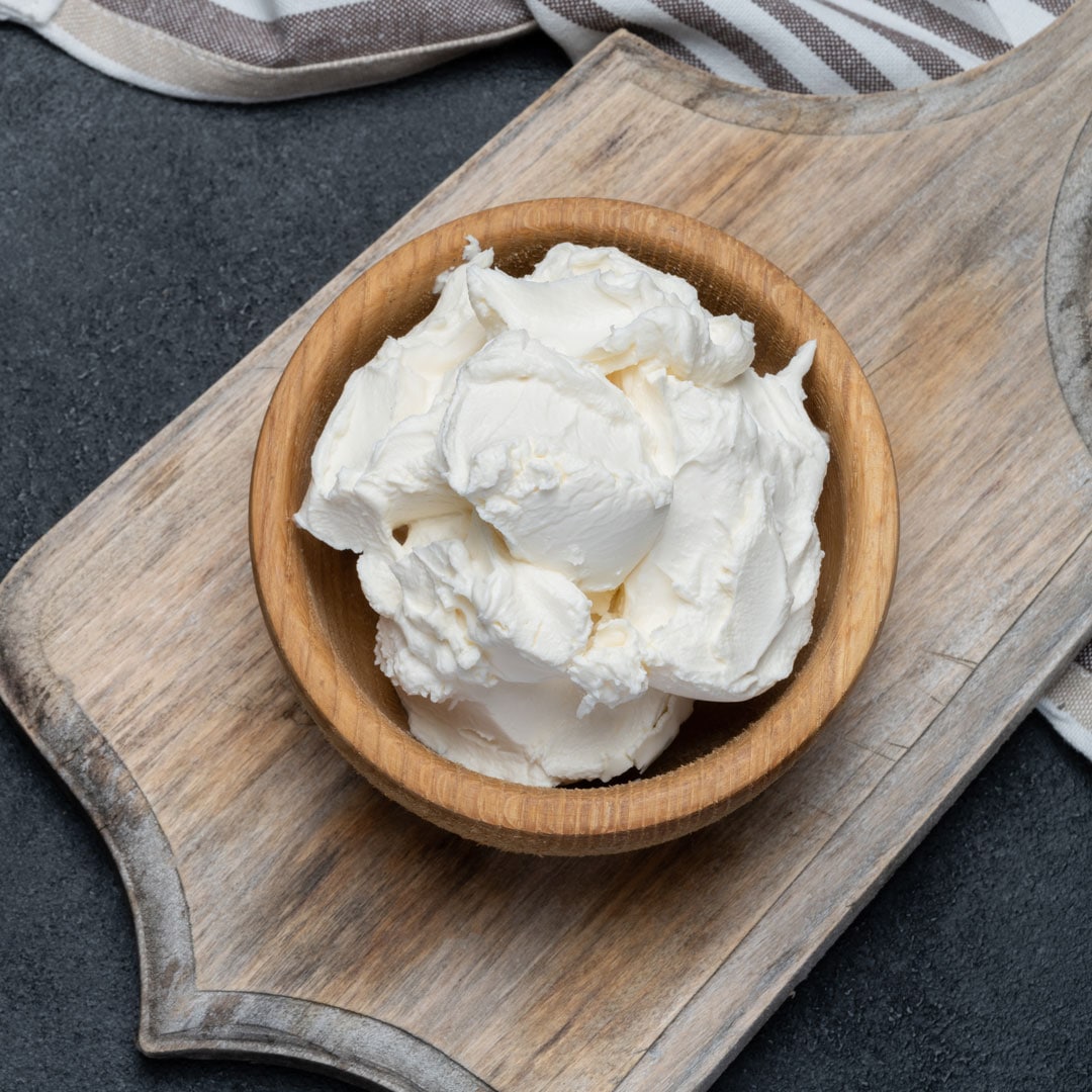 Schale mit Frischkäse auf Holzbrett