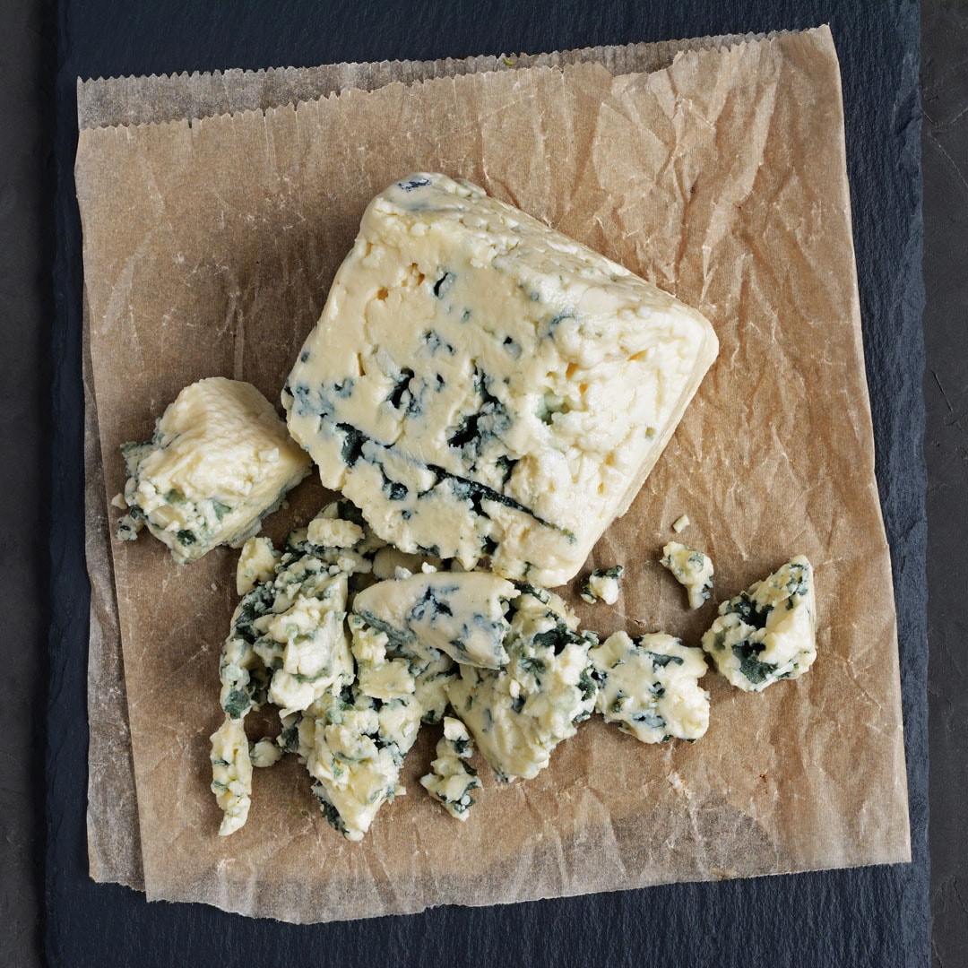 Halbfester Schnittkäse auf Backpapier auf Schiefer
