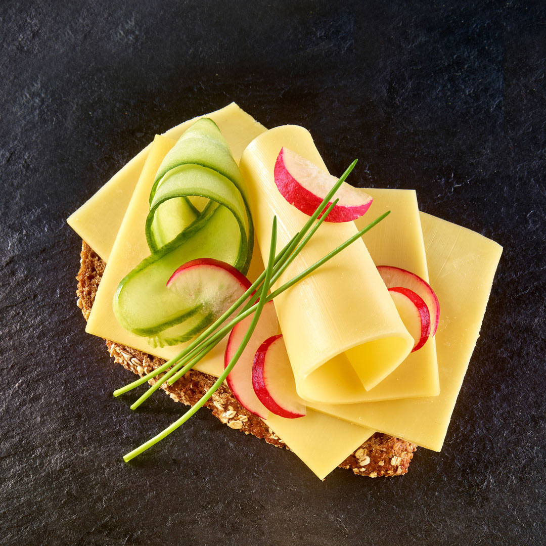 Schnittkäse und Gurke und Radieschen auf halbem Brötchen
