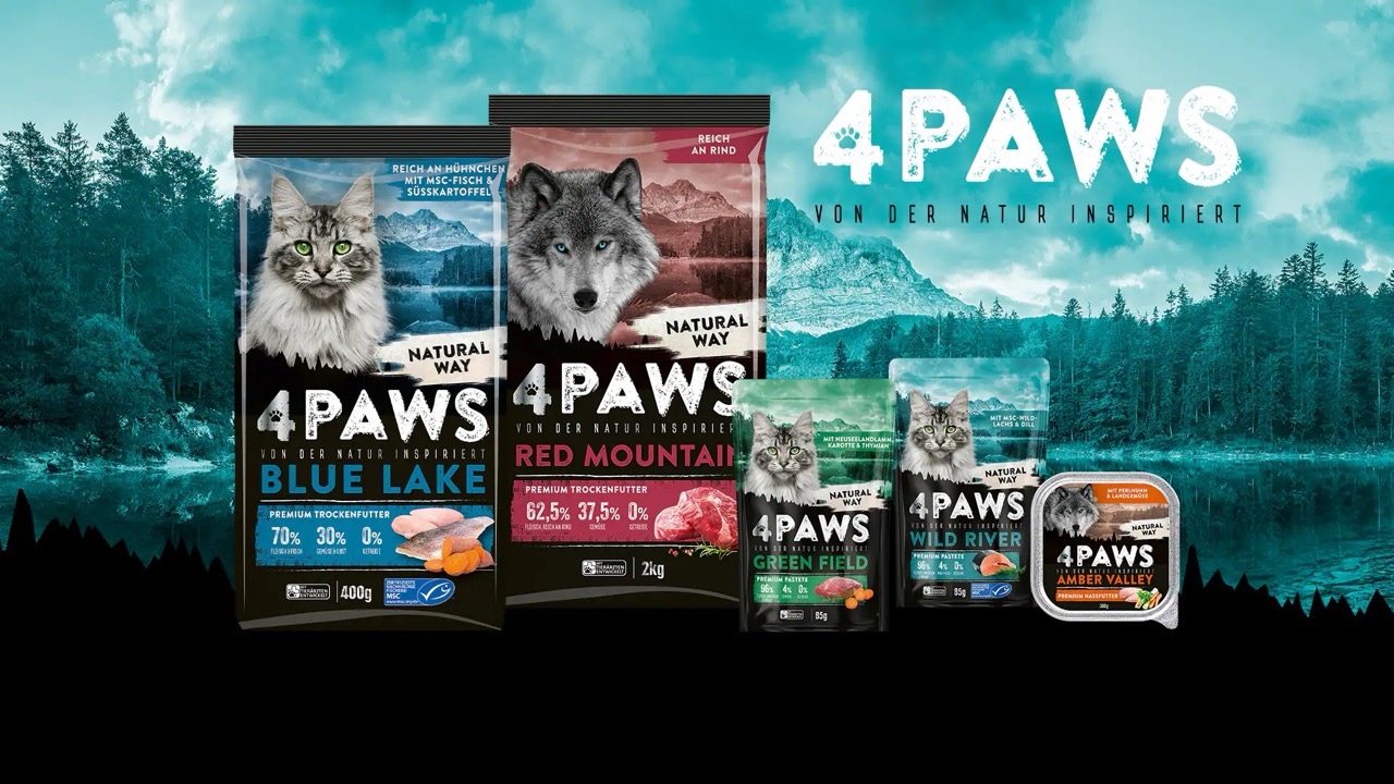 Verschiedene Packungen Katzen- und Hundefutter der Marke 4PAWS vor Wald- und Bergkulisse.
