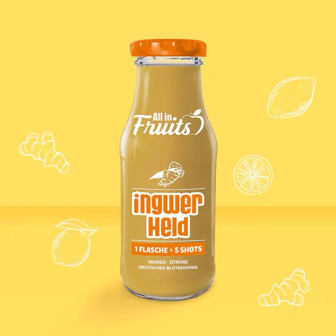 All in Fruits Ingwershots mit Ingwer, Zitrone und deutschem Blütenhonig. Bräunlicher Inhalt vor gelbem Hintergrund.