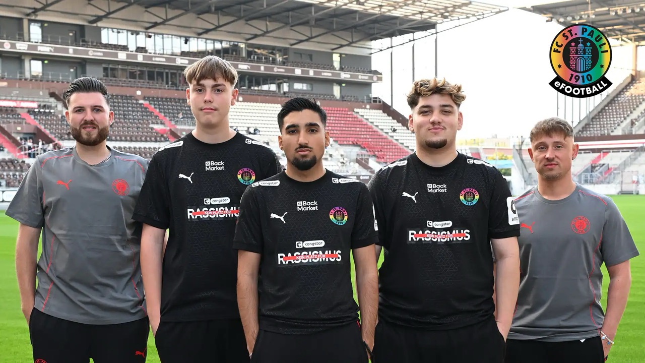 Fünf Männer auf dem Rasen eines Fußballstadions. Alle tragen Shirts mit dem Logo des FC St. Pauli.