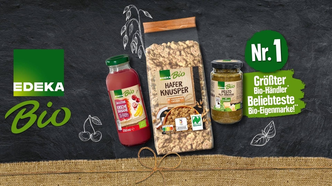 Drei EDEKA Bio Produkte auf dunklem Steinuntergrund: Kirsche-Banane-Smoothie, Hafer Knusper Müsli und Pesto alla Genovese. Links das EDEKA Bio Logo, rechts die Aufschrift „Nr. 1. Größter Bio-Händler*, Beliebteste Bio-Eigenmarke!**“.