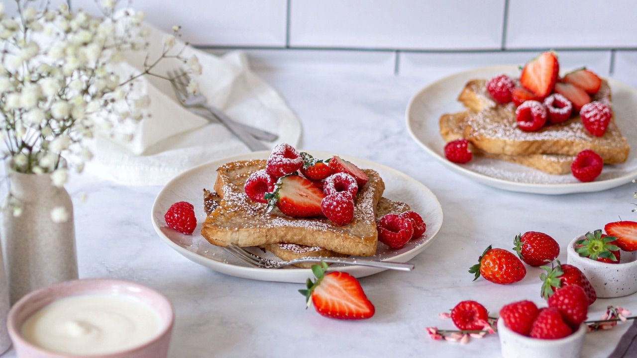 Mit Himbeeren, Erdbeeren und Puderzucker dekorierter French Toast auf einem weißen Teller.