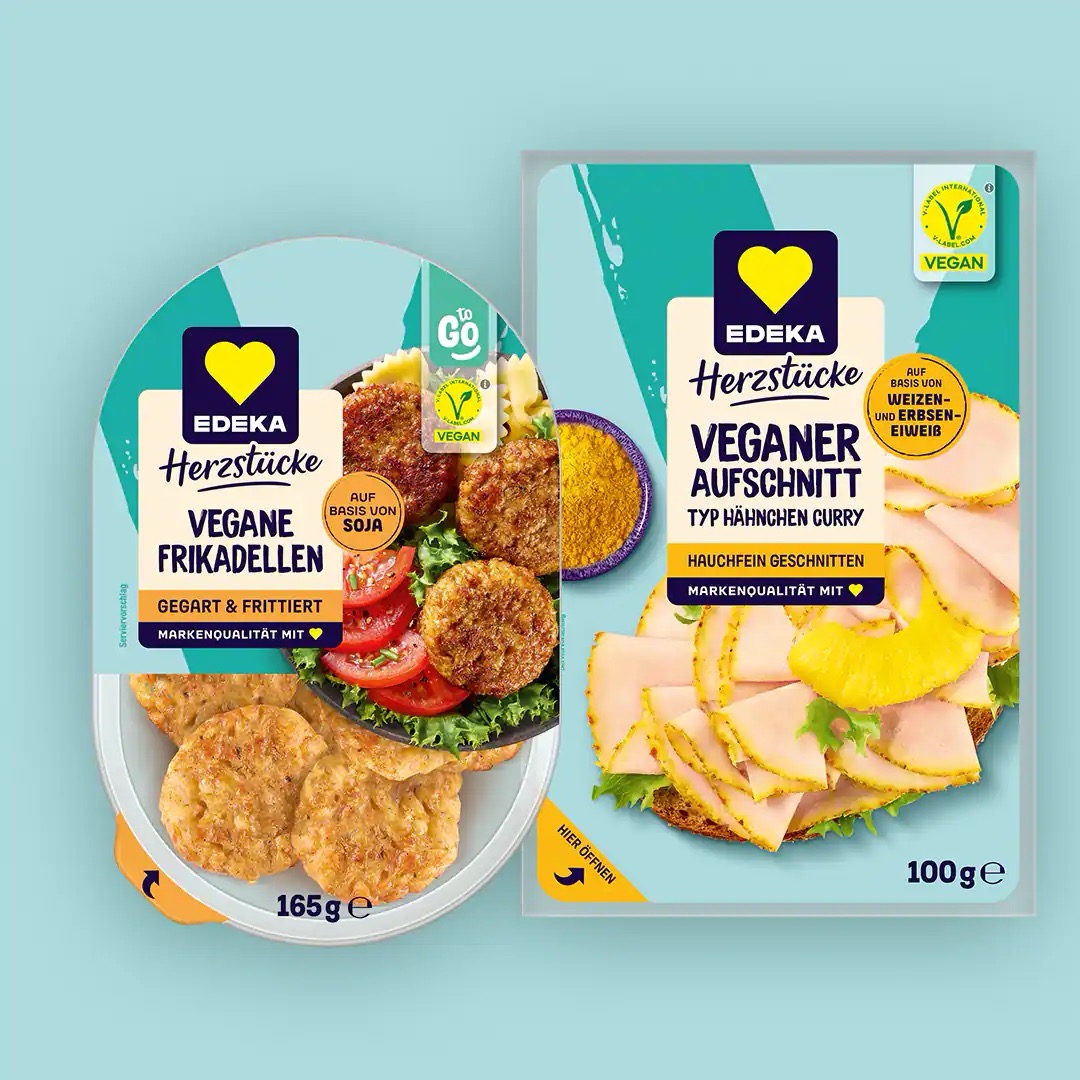 Eine Packung vegane Frikadellen sowie veganer Aufschnitt Typ Hähnchen Curry von EDEKA Herzstücke.