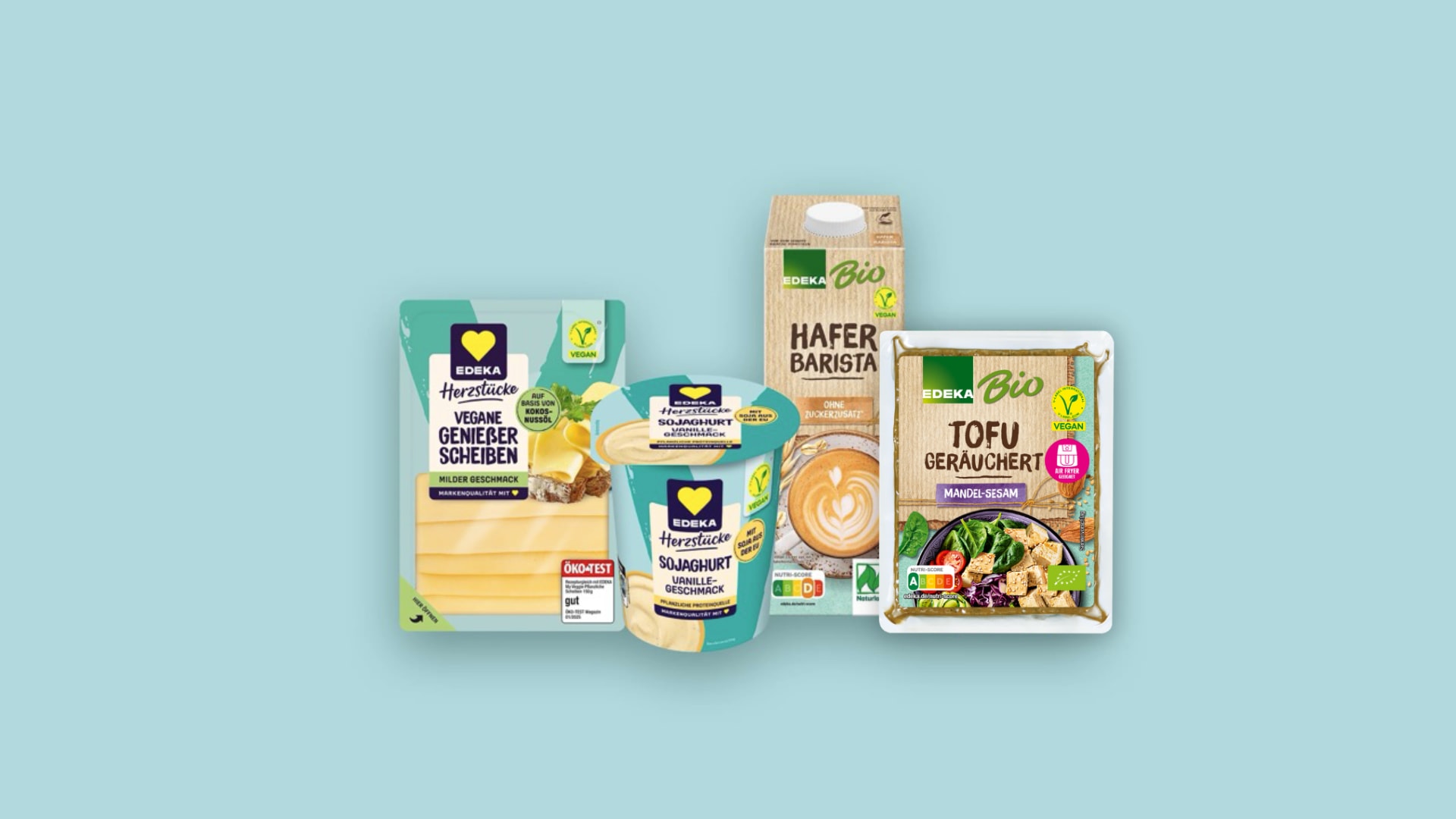 Vier Produkte vor hellblauem Hintergrund: Vegane Genießer Scheiben und Sojaghurt Vanille von EDEKA Herzstücke sowie Hafer Drink Barista und Tofu geräuchert Mandel-Sesam