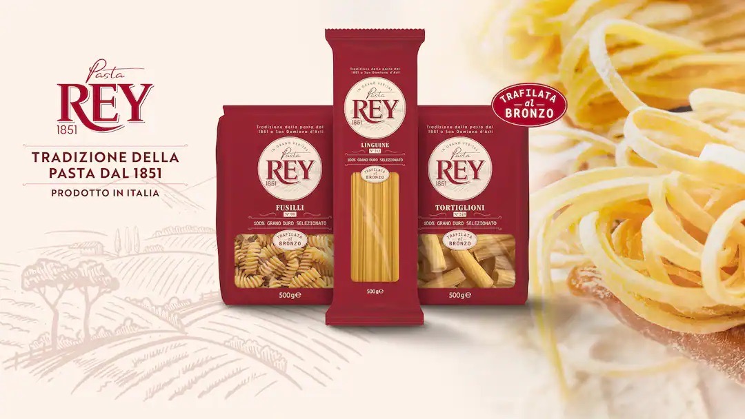 Rote Verpackungen von Pasta REY 1851 neben einem Teller zubereiteter Pasta.