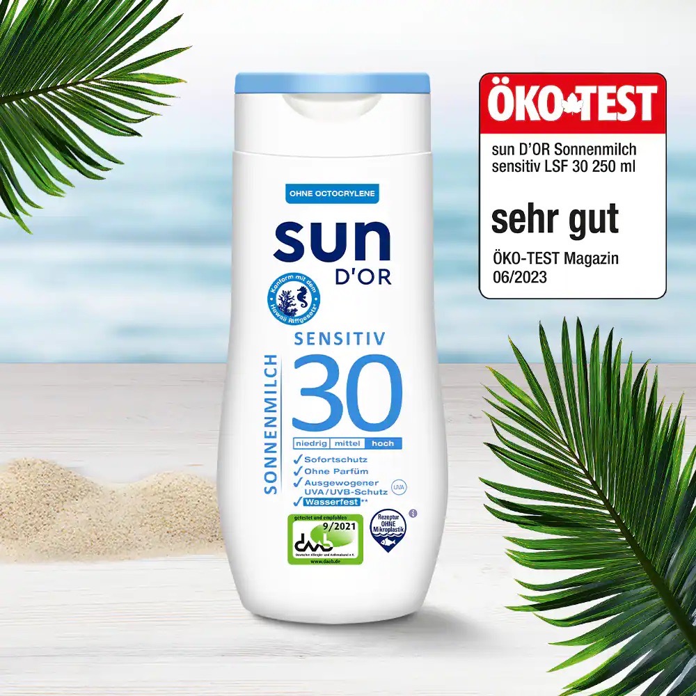 Weiße Packung Sonnenmilch sensitiv 30 von Sun D´Or. Im Hintergrund ein Strand und ein Horizont.