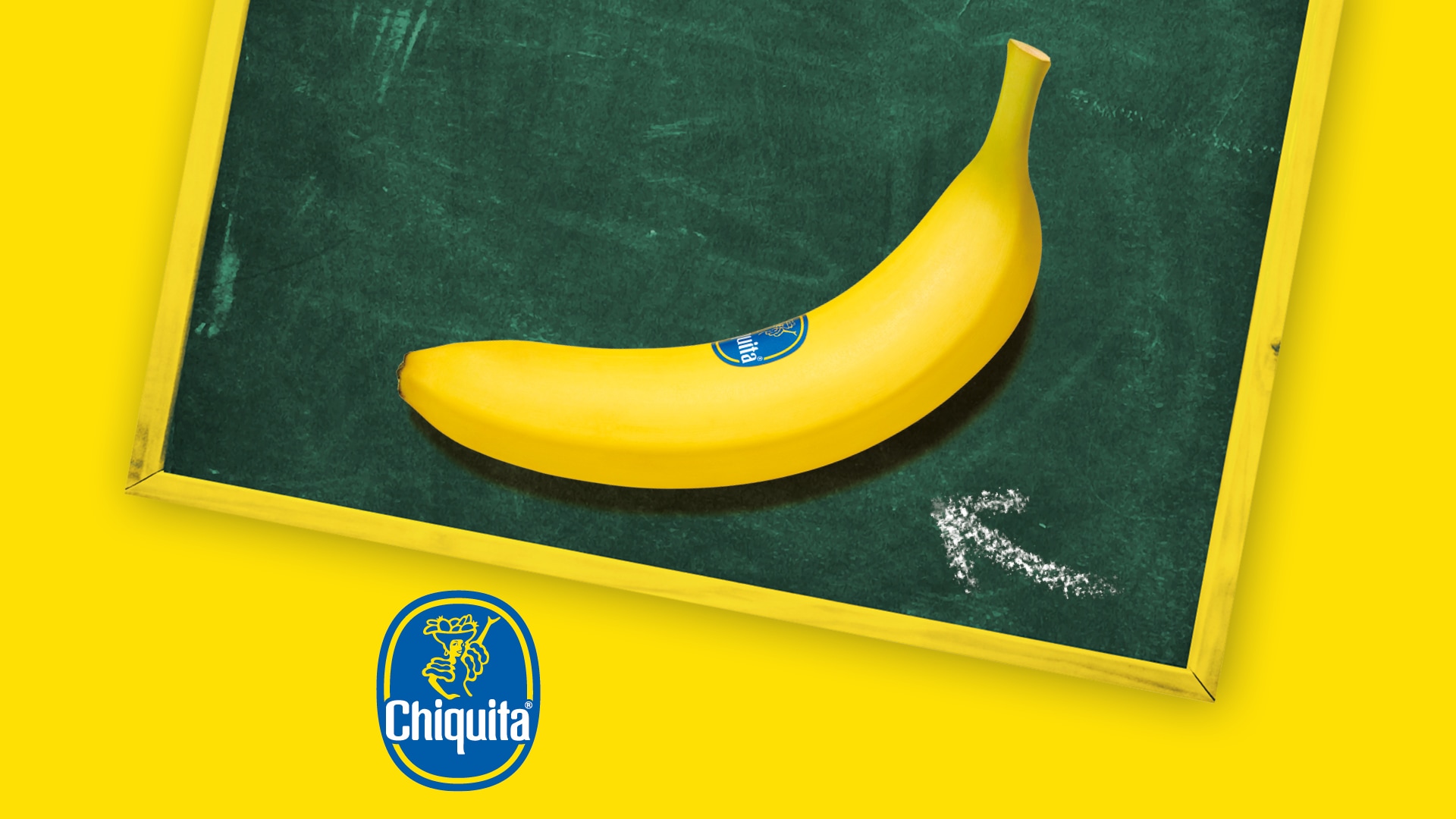Gelbe Chiquita-Banane auf einer grünen Schultafel vor gelbem Hintergrund, mit Chiquita-Logo und Kreidezeichnung.