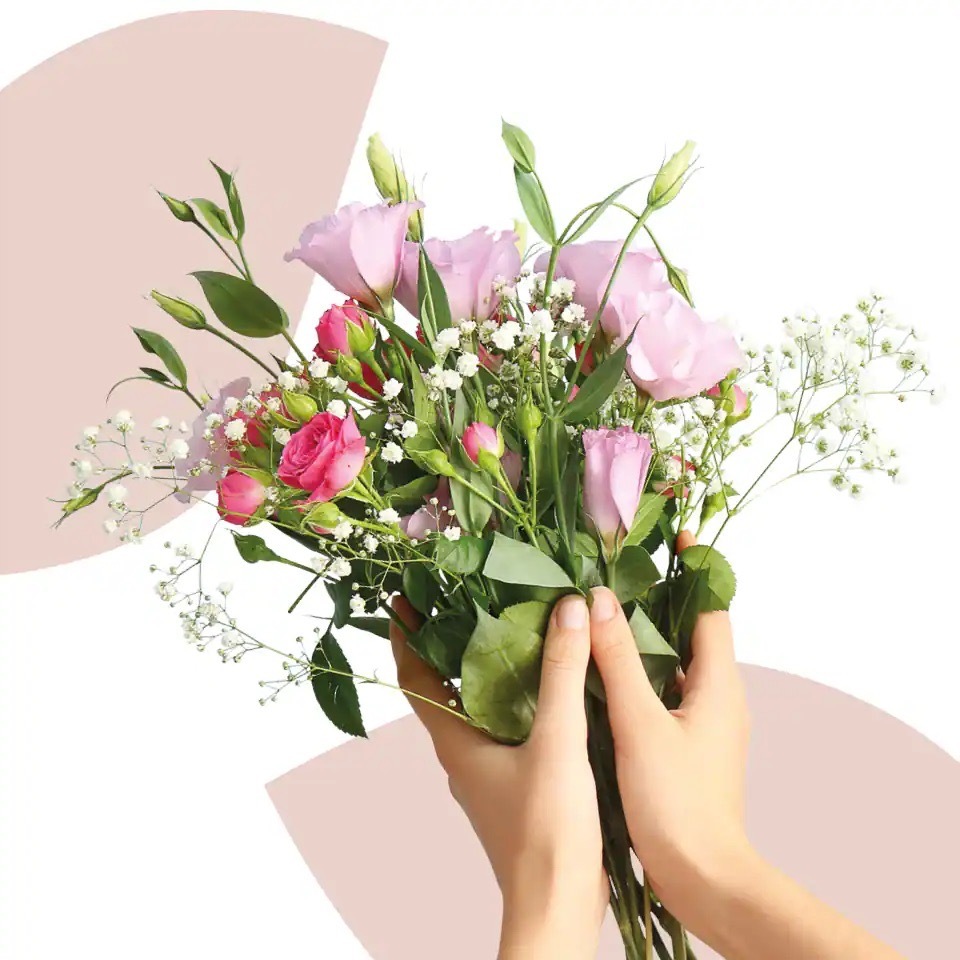 Zwei Hände halten einen kleinen Blumenstrauß mit rosanen Rosen und weißen Blüten.