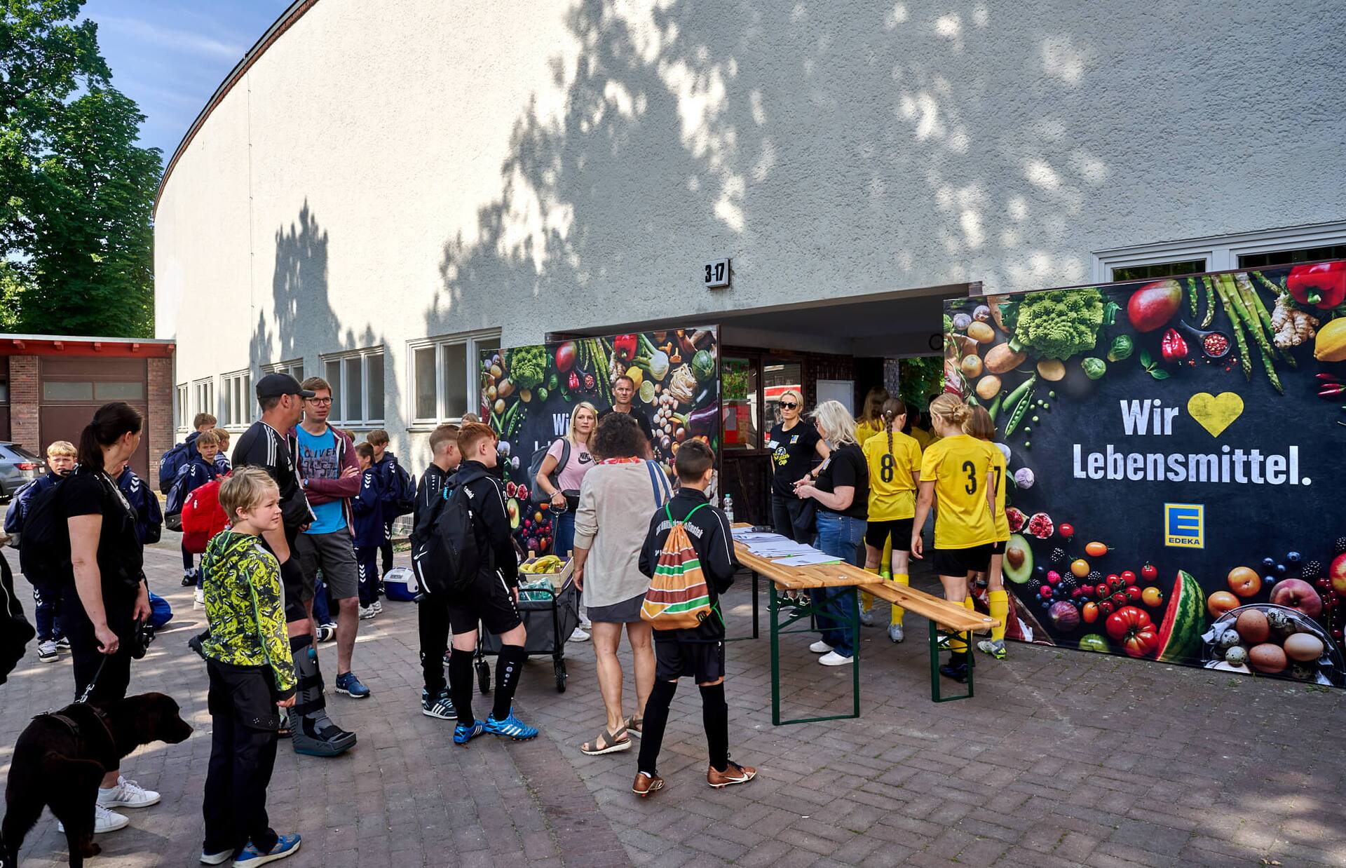 Jugend-Fußball-Spielerinnen bewegen sich in Richtung Eingang eines Gebäudes.