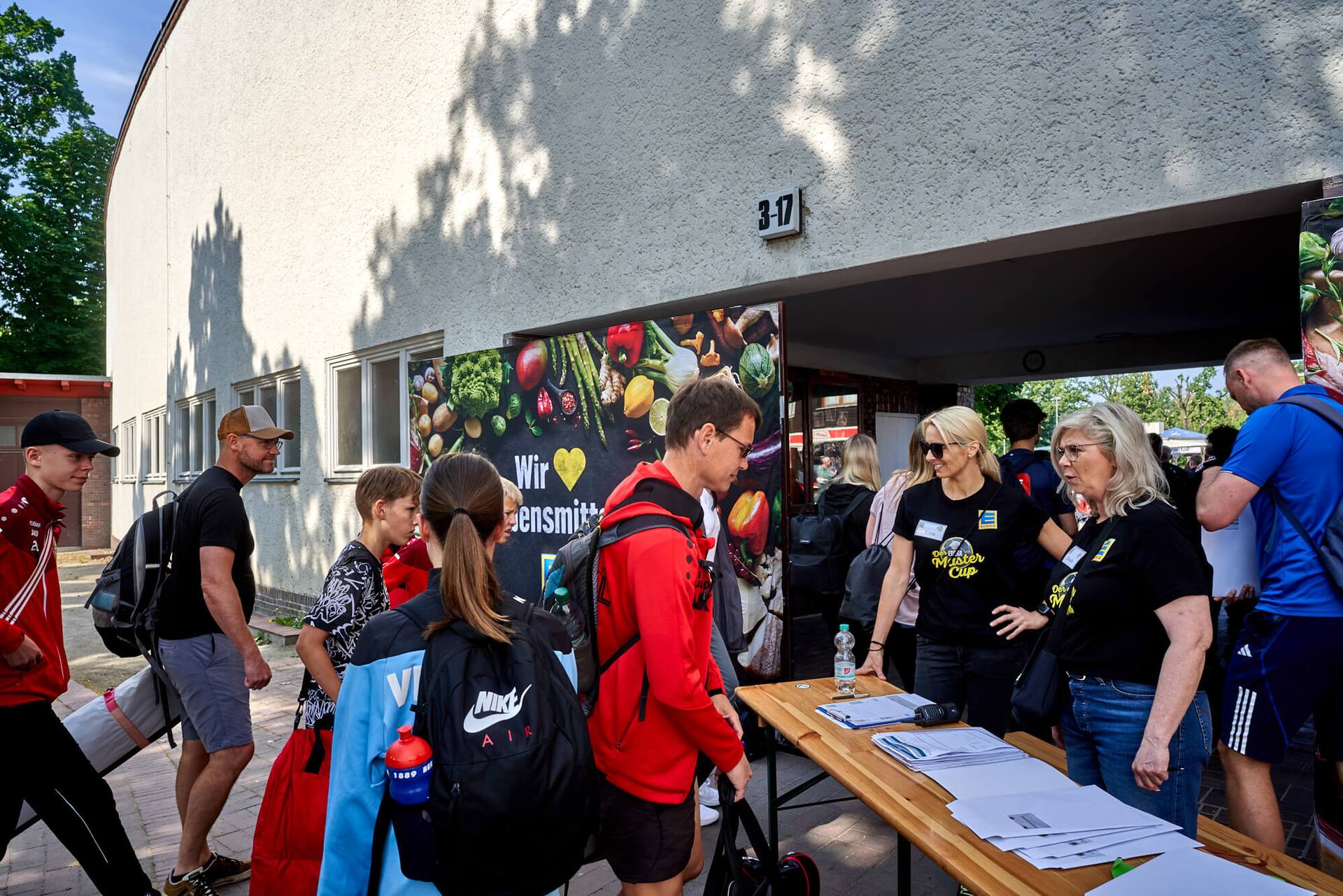 Anmeldung der Jugendfußball-Teams vor einem Gebäude.