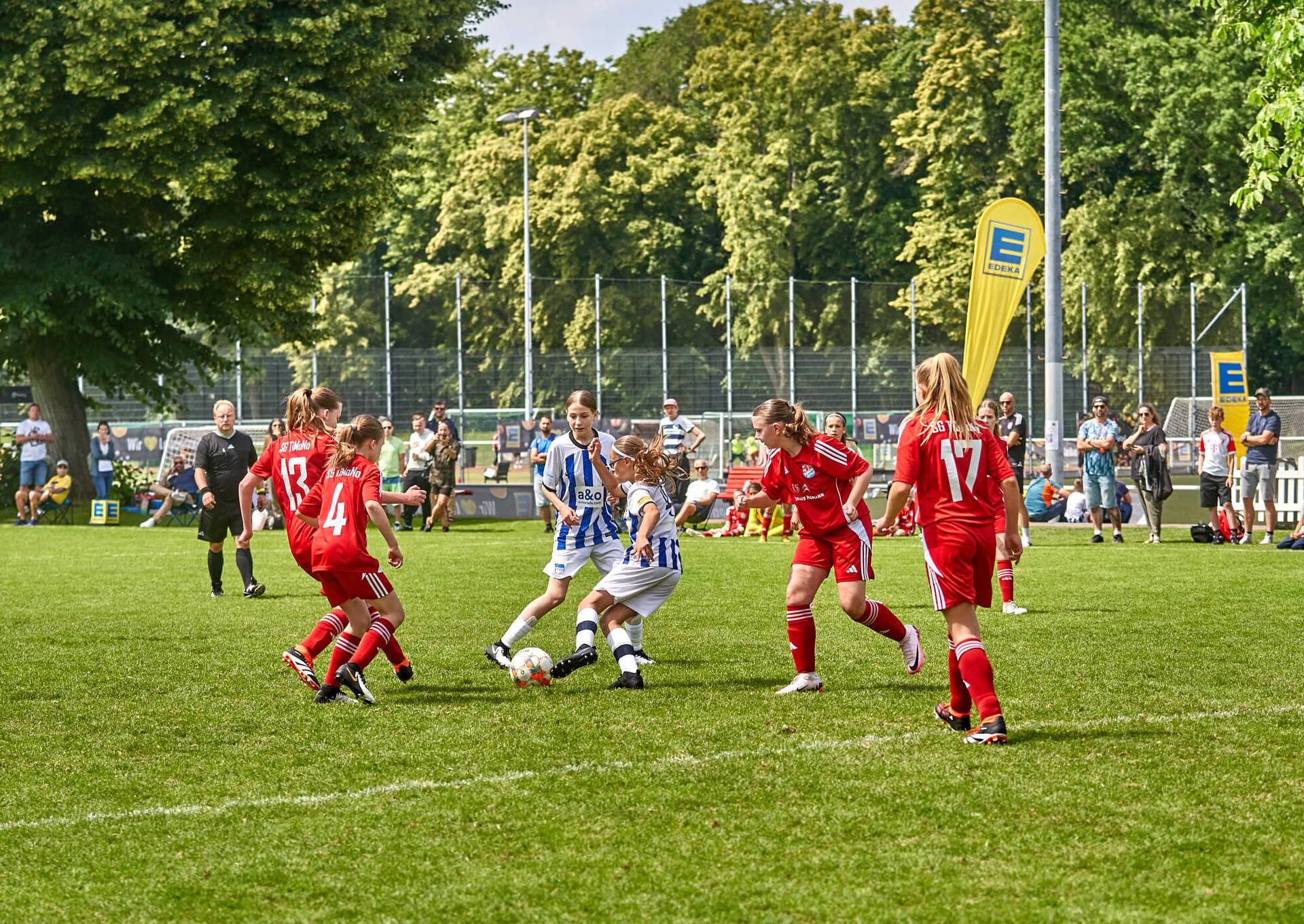 Eine Fußball-Jugendspielerin wird von drei Gegnerinnen bedrängt und versucht, den Ball zu einer Mitspielerin zu passen.