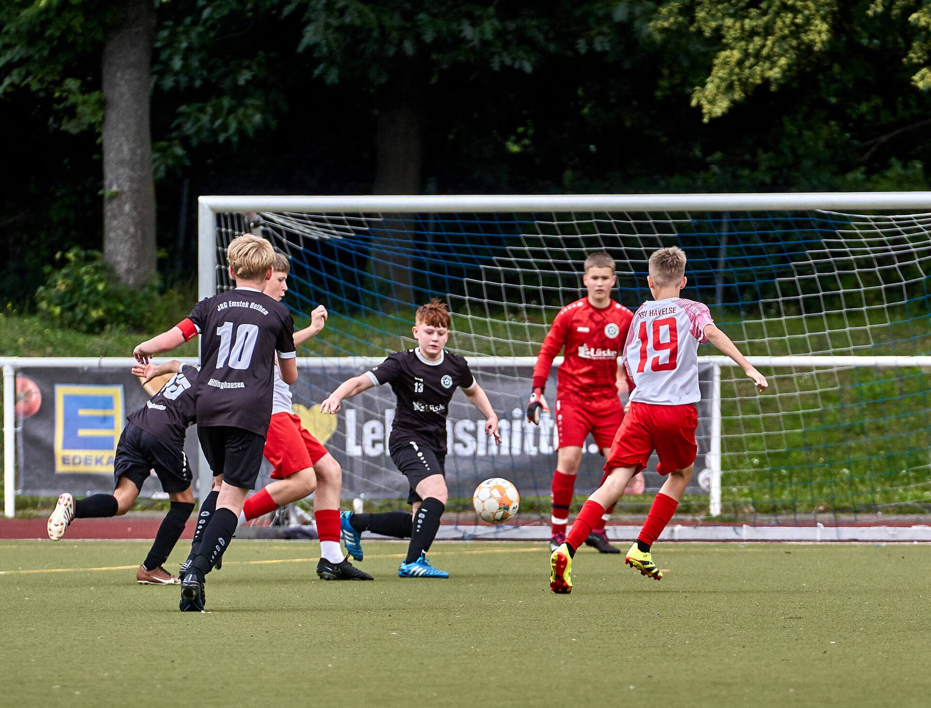 Ein Jugendspieler holt zum Schuss aus. Im Hintergrund erwartet der Torhüter den Ball.